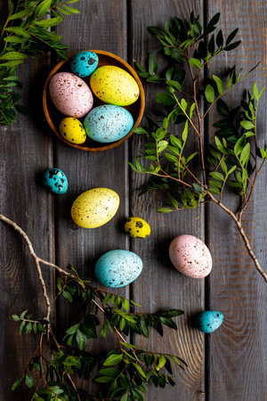 Easter eggs with spring branches on wooden board. Top view