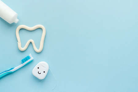Tooth shape with tube of toothpaste and toothbrush. Dental hygiene concept, top view