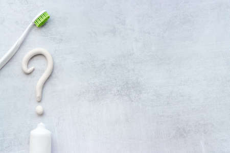 Question mark of toothpaste with toothbrush, top view. Oral care and hygiene