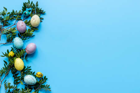Frame of Easter eggs with spring branches and green leaves. Veiw from above