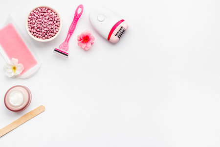 Set of epilation means - epilator with wax strips, razor and flowers. Top view