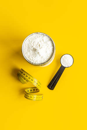 Whey protein in scoop and jar with tape measure. Sport nutritionの写真素材