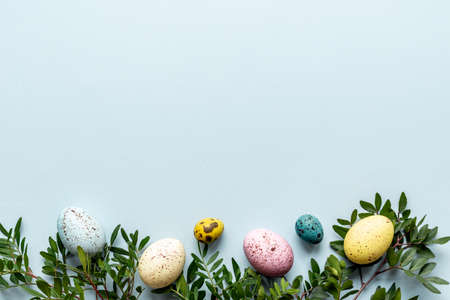 Frame of Easter eggs with spring branches and green leaves. View from above