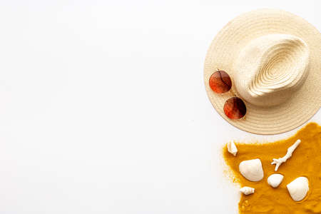 Beach accessories on sand with seashells, sraw hat and sun glasses