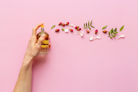 Female hand spray perfume bottle and flow of flowers