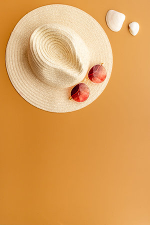 Straw beach womans hat with sun glasses on sand. Top view