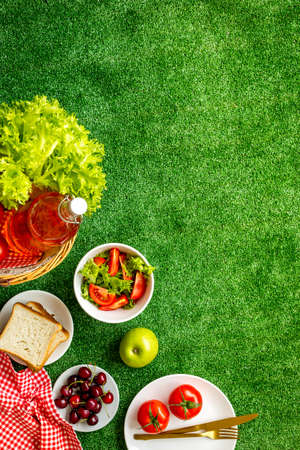 Summer picnic setting. Basket with food on red cloth, top viewの写真素材