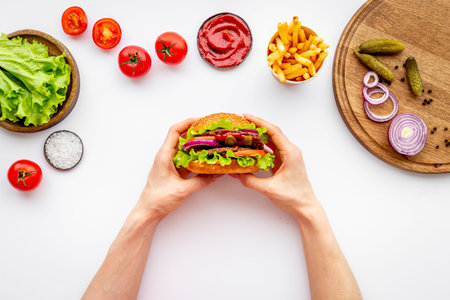 Female hands holding hamburger. Sandwich burger with ingredients. Fastfood meal backgroundの写真素材
