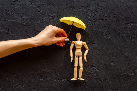 Hand with umbrella cover wooden mannequin figure. Social protection and insurance conceptの写真素材
