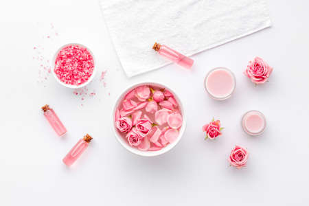 Cosmetics with rose oil essence. Face cream lotion and flowers, top viewの写真素材