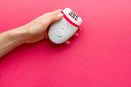 Female hand with white epilator for hair removal. Depilatory overhead viewの写真素材