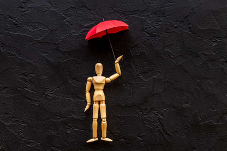 Social protection and insurance concept. Umbrella cover wooden mannequin figure.の写真素材