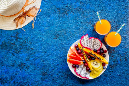 Exotic fruit salad in white plate. Fruits with fresh juice and hat, top viewの写真素材