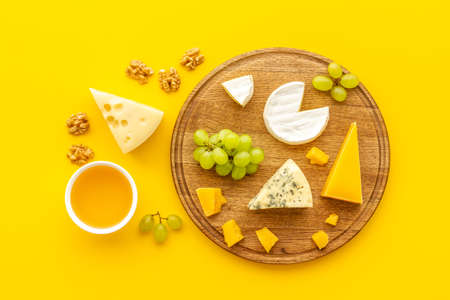 Set of cheese with honey and grapes on wooden boardの写真素材