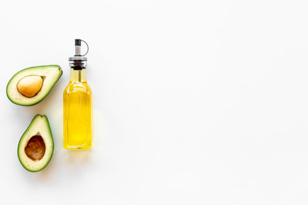 Avocado oil in glass bottle with fresh avocado.