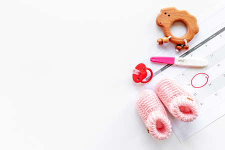 Pregnancy test with pink baby girl booties and calendar, top viewの写真素材