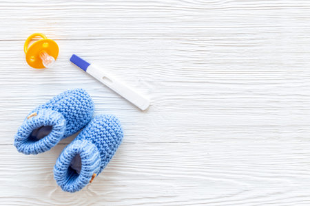 Pregnancy test and blue baby boy booties. Morherhood and pregnancy concept