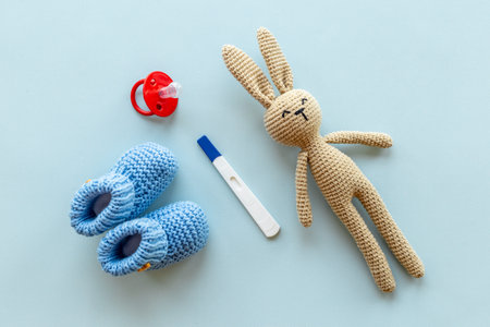 Pregnancy test with blue baby boy booties and toy, top view