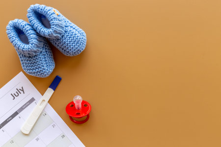 Pregnancy test with blue baby boy booties and calendar, top view