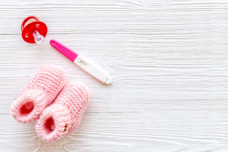 Pregnancy test and pink baby girl booties. Motherhood and pregnancy conceptの写真素材