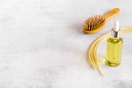 Hair essential oil with wooden brush and blond curl of hair