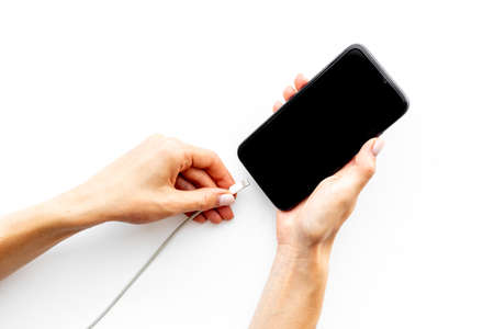 Woman hands connecting smartphone to charge cableの写真素材