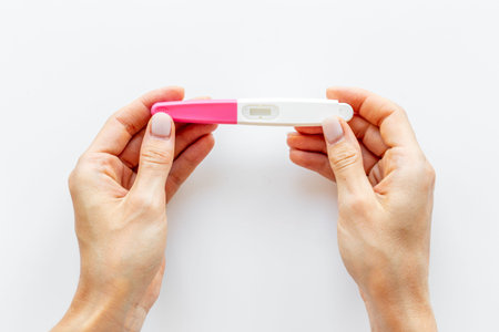 Woman holding pregnancy test, top view. Pregnant female health care concept