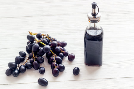 Red wine vinegar in glass bottle with bunch of black grapes