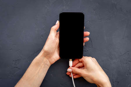 Woman hands connecting smartphone to charge cableの写真素材