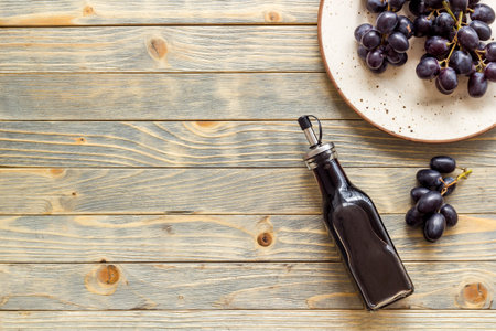 Bottle of balsamic vinegar with bunch of fresh grapes