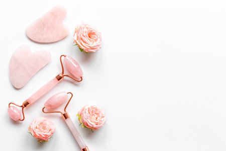 Pink gua sha massage stone and face roller with rose flowers