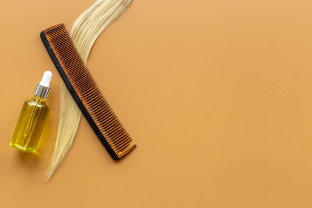 Essential oil for hair care with wooden hair comb and blond curl