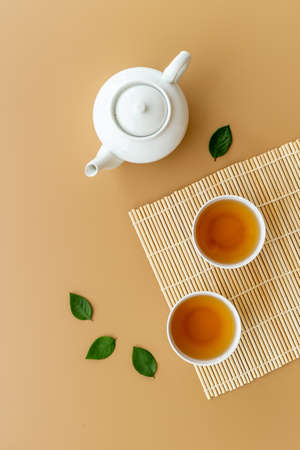 Black tea in cups with white teapot and green leavesの写真素材