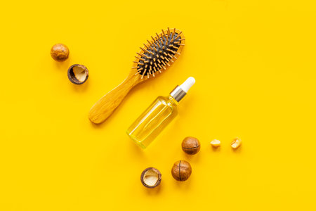 Macadamia oil for hair care with wooden hair brush. Top view