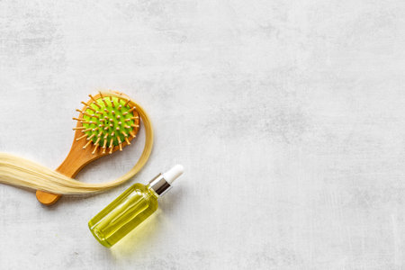 Hair essential oil with wooden brush and blond curl of hairの写真素材