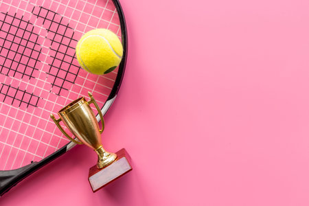 Small golden trophy cup with tennis racket and ball. Sport champion winner concept