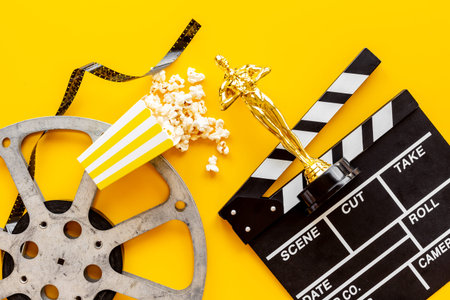 Golden movie award statue with film reel video tape and clapper board