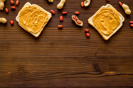Creamy peanut butter and nuts in wooden bowls, top view