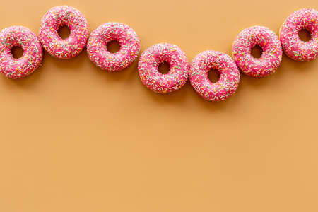 Set of pink glazed donuts with sprinkles, top view