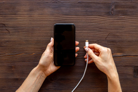 Woman hands connecting smartphone to charge cable