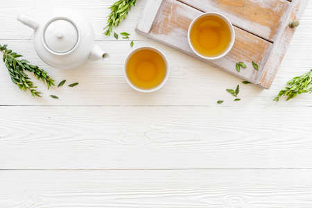 Tea drinking with white teapot and two cups with green leaves, top viewの写真素材