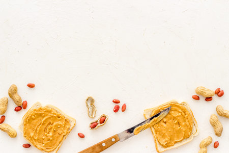 Smooth peanut butter on sandwiches with nuts. Top view