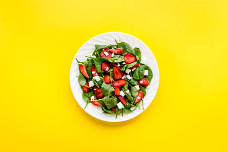 Green spinach salad with red strawberry and goat cheese, top viewの写真素材