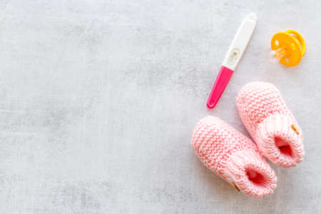 Pink baby girl booties with pregnancy test. Morherhood and pregnancy conceptの写真素材