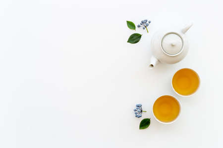 Black tea in cups with white teapot and green leavesの写真素材