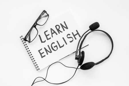 English lessons concept. Headpones with notebook on student table deskの写真素材