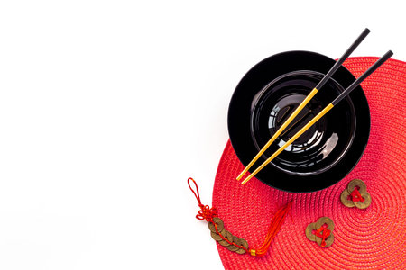 Golden chopsticks on black bowl with red napkin. Asian table place setting