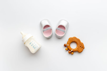 Baby newborn pink booties with bottle of milk and wooden toy
