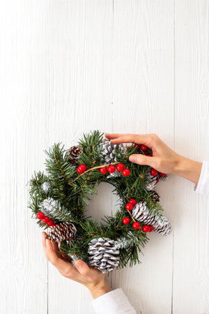 Female hands holding festive Christmas wreath. New year decoration backgroundの写真素材