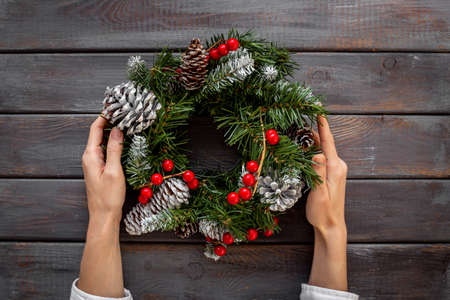 Female hands holding festive Christmas wreath. New year decoration backgroundの写真素材